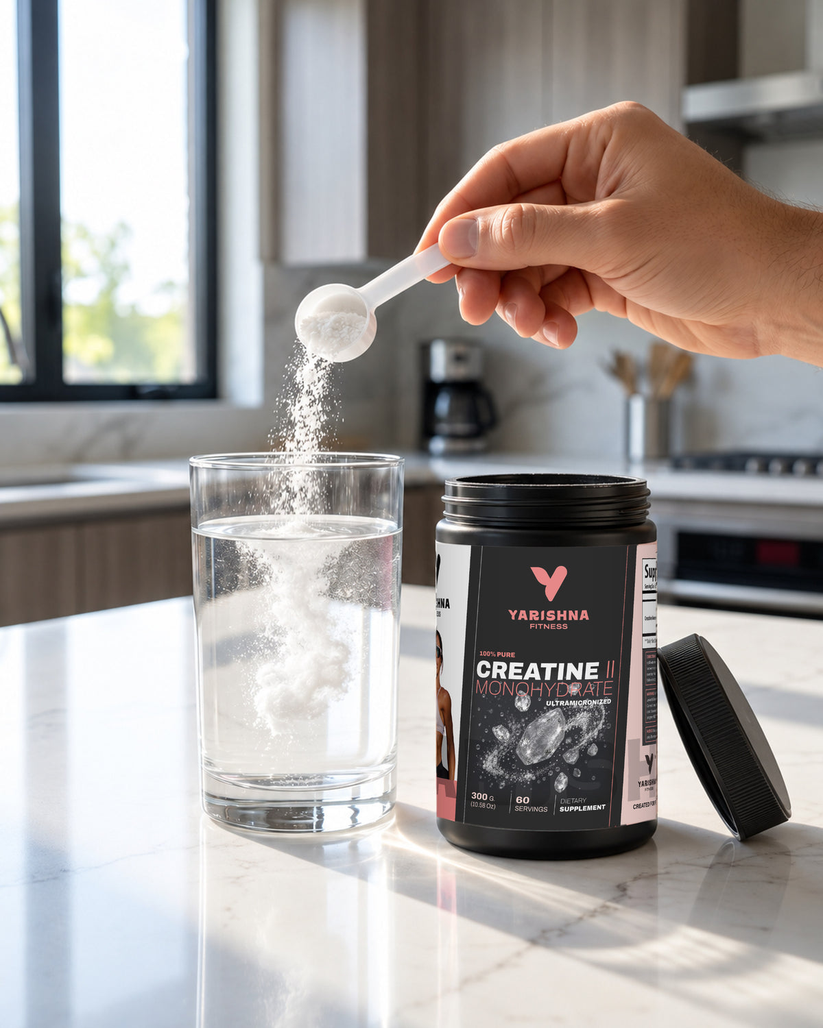 A scoop of 100% Creatine Monohydrate powder being poured into a glass of water, next to the Yarishna Fitness tub