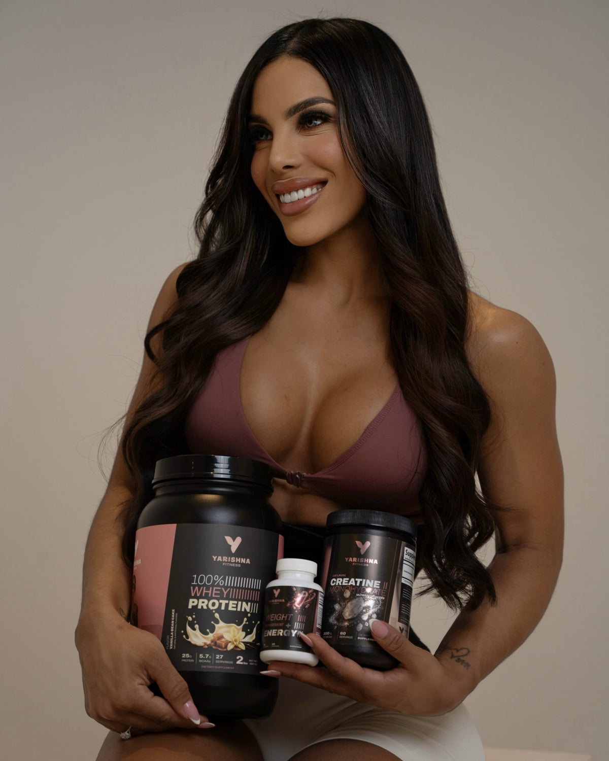 Yarishna Ayala holding 100% Whey Protein, 100% Creatine and Weight Management + Energy